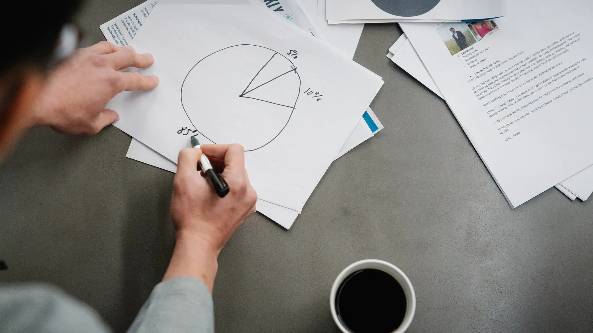 Someone sketches a pie chart split into budget percentages on paper